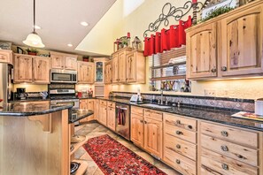 A modern kitchen with wooden cabinets, stainless steel appliances, and a black granite countertop. - Expansive Angel Fire Retreat: 1 Mi to Fishing! (Angel Fire)