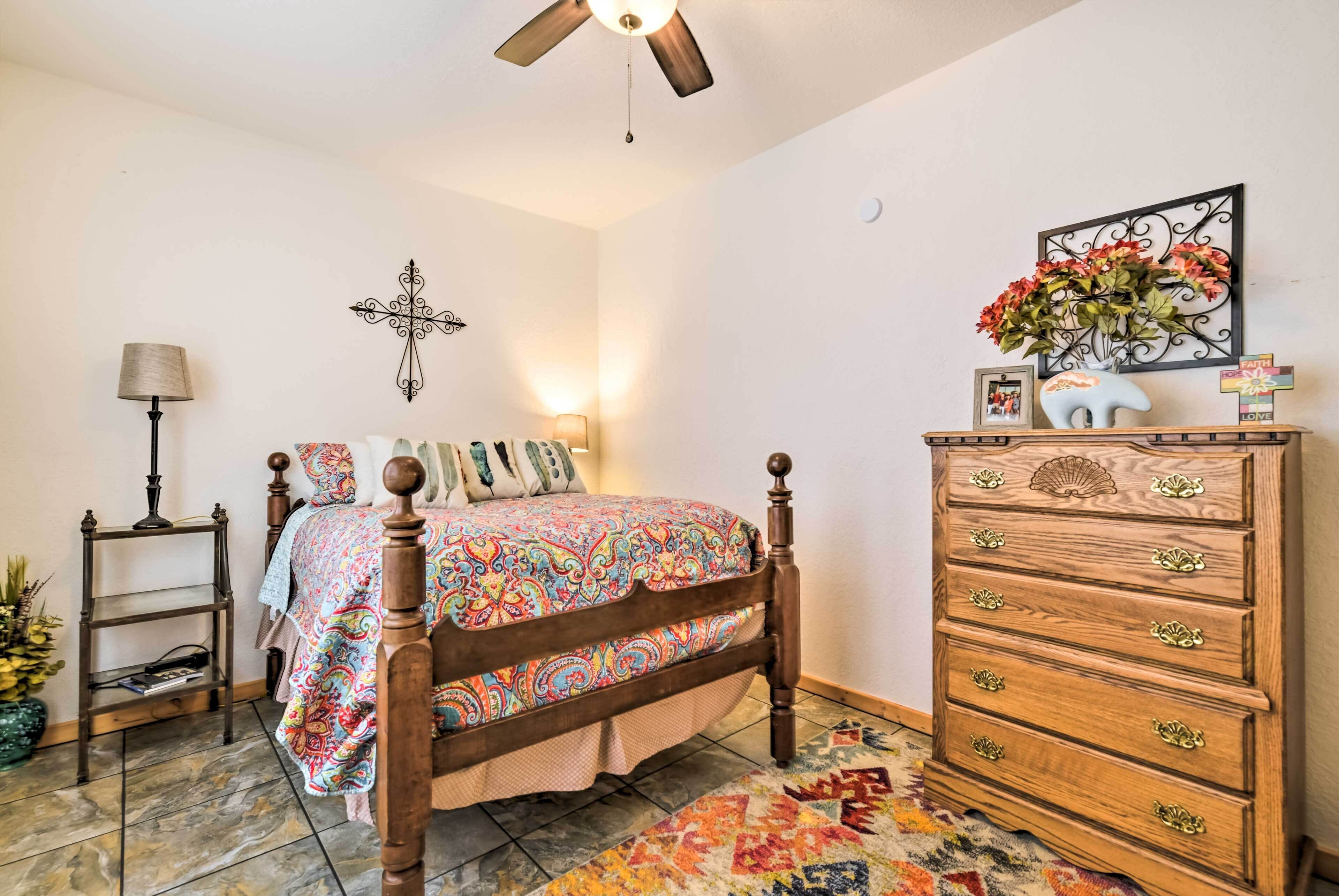 Une chambre à coucher avec un lit en bois, une commode, une croix accrochée au mur et une lampe.