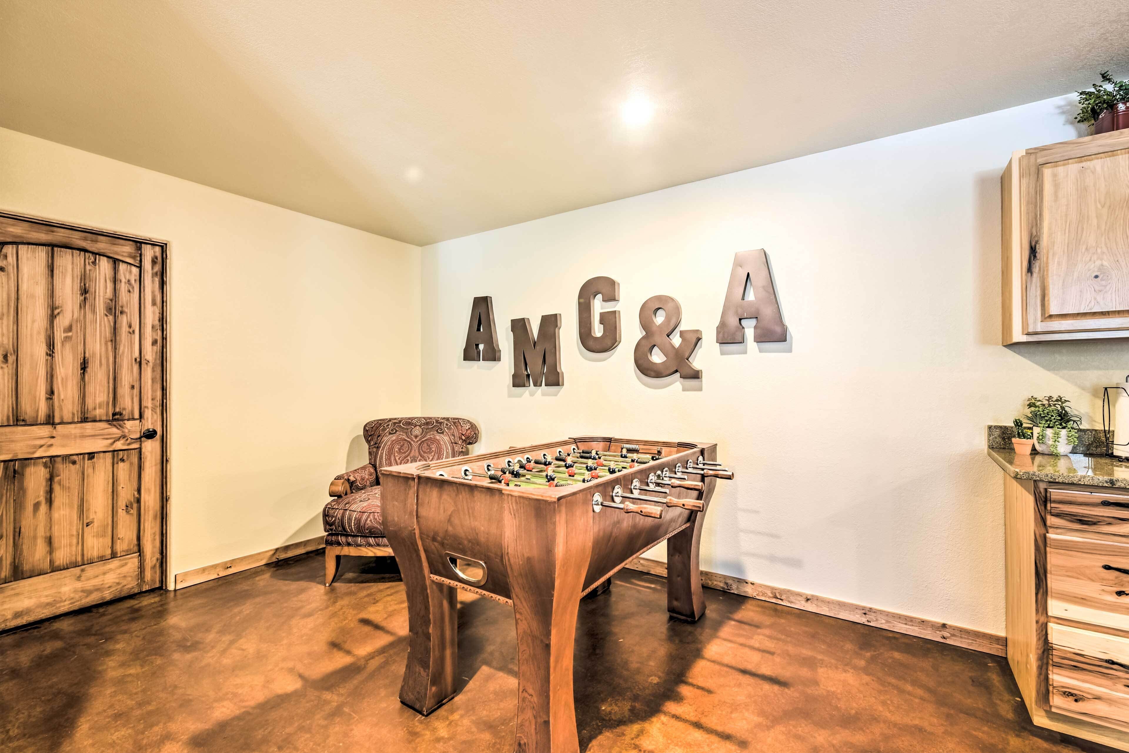 A room with a foosball table, a wooden cabinet, and a wall-mounted sign reading "AMG&A".