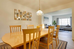 A dining area with a wooden table and chairs, a hanging light fixture, and a painting on the wall. - Spacious Thornton Home: 15 Mi to Downtown Denver! (Thornton)
