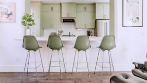 A modern kitchen with green cabinets, a white countertop, and three green bar stools. - Sacramento Guest House w/ Patio ~ 5 Mi to Downtown (Sacramento)
