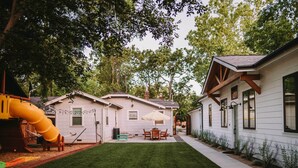 A backyard with a play area, a patio with a table and chairs, and a house with a white exterior and wooden accents. - Sacramento Guest House w/ Patio ~ 5 Mi to Downtown (Sacramento)