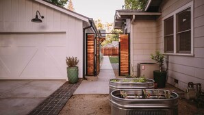 A narrow driveway leading to a garage with a wooden door, potted plants, and metal containers. - Sacramento Guest House w/ Patio ~ 5 Mi to Downtown (Sacramento)