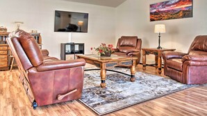 A modern living room with leather recliners, a flat-screen TV, a painting, and a wooden coffee table.