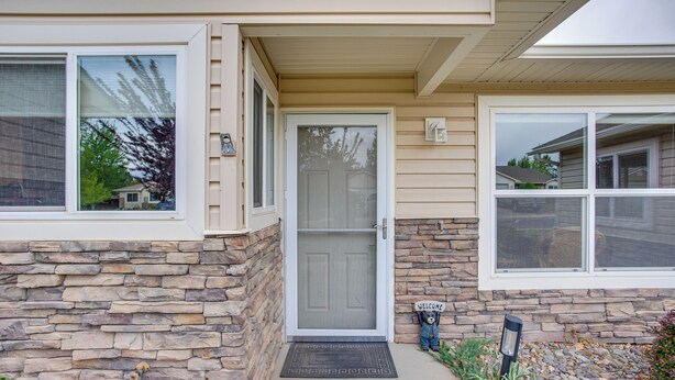 A house with a stone exterior, a front door, and a welcome sign.