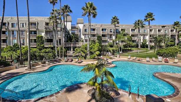 Un hotel con una piscina grande rodeada de palmeras y un césped bien cuidado.