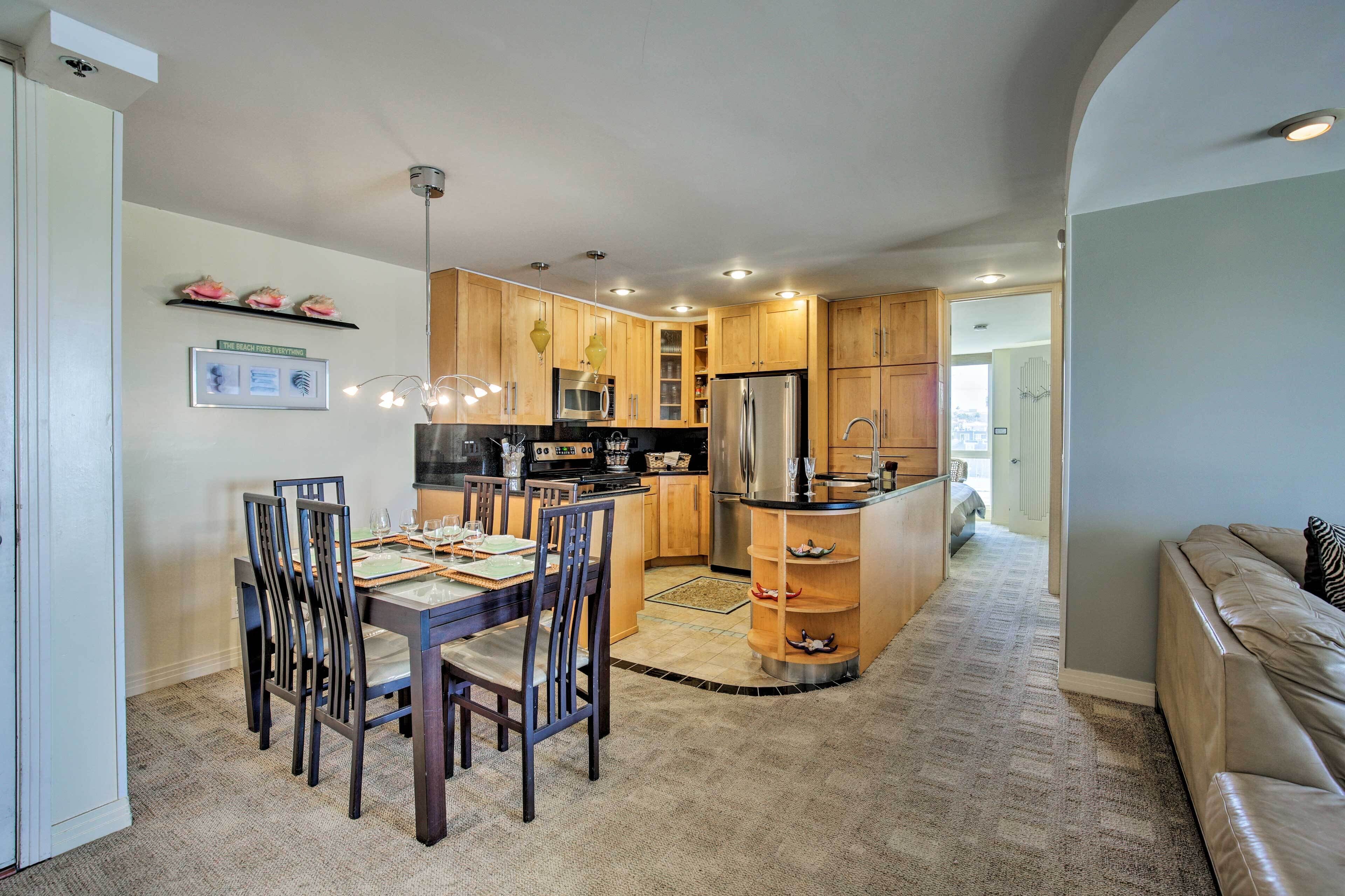 A modern kitchen with wooden cabinets, a stainless steel refrigerator, and a dining area with a table and chairs.