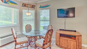A dining area with a glass table and wicker chairs, a wooden cabinet, and a TV mounted on the wall. - Resort Condo in Pottsboro w/ Lake Texoma Access! (Pottsboro)