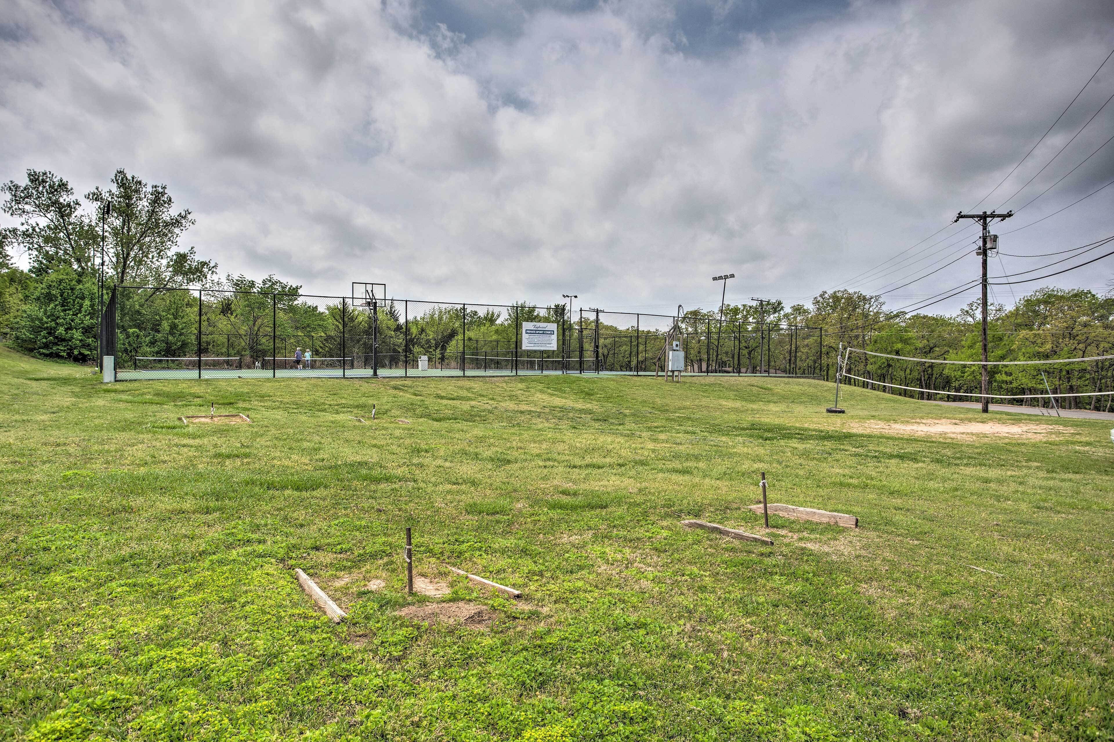 A sports field with a fence, trees, and a cloudy sky.