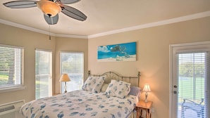 A bedroom with a bed, two bedside lamps, a ceiling fan, and a beach-themed painting on the wall. - Resort Condo in Pottsboro w/ Lake Texoma Access! (Pottsboro)