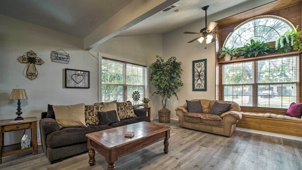 A spacious living room with a wooden coffee table, two sofas, and a large window with plants. - Bright College Station Abode: 3 Mi to Kyle Field (Bryan)