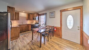 Una cocina con armarios de madera, un refrigerador, un microondas y una mesa de comedor preparada para cuatro personas.
