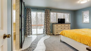 A bedroom with a bed, a dresser, a television, and a view of a snowy landscape through the window. - Spacious and Lakefront Wasilla Home (Wasilla)