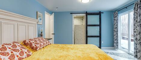 A bedroom with a bed, a door, and a window with curtains.