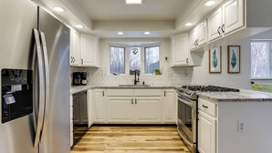 A modern kitchen with white cabinets, a stainless steel refrigerator, a built-in oven, and a granite countertop. - Spacious and Lakefront Wasilla Home (Wasilla)