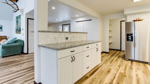 A modern kitchen with white cabinets, granite countertops, and a stainless steel refrigerator. - Spacious and Lakefront Wasilla Home (Wasilla)