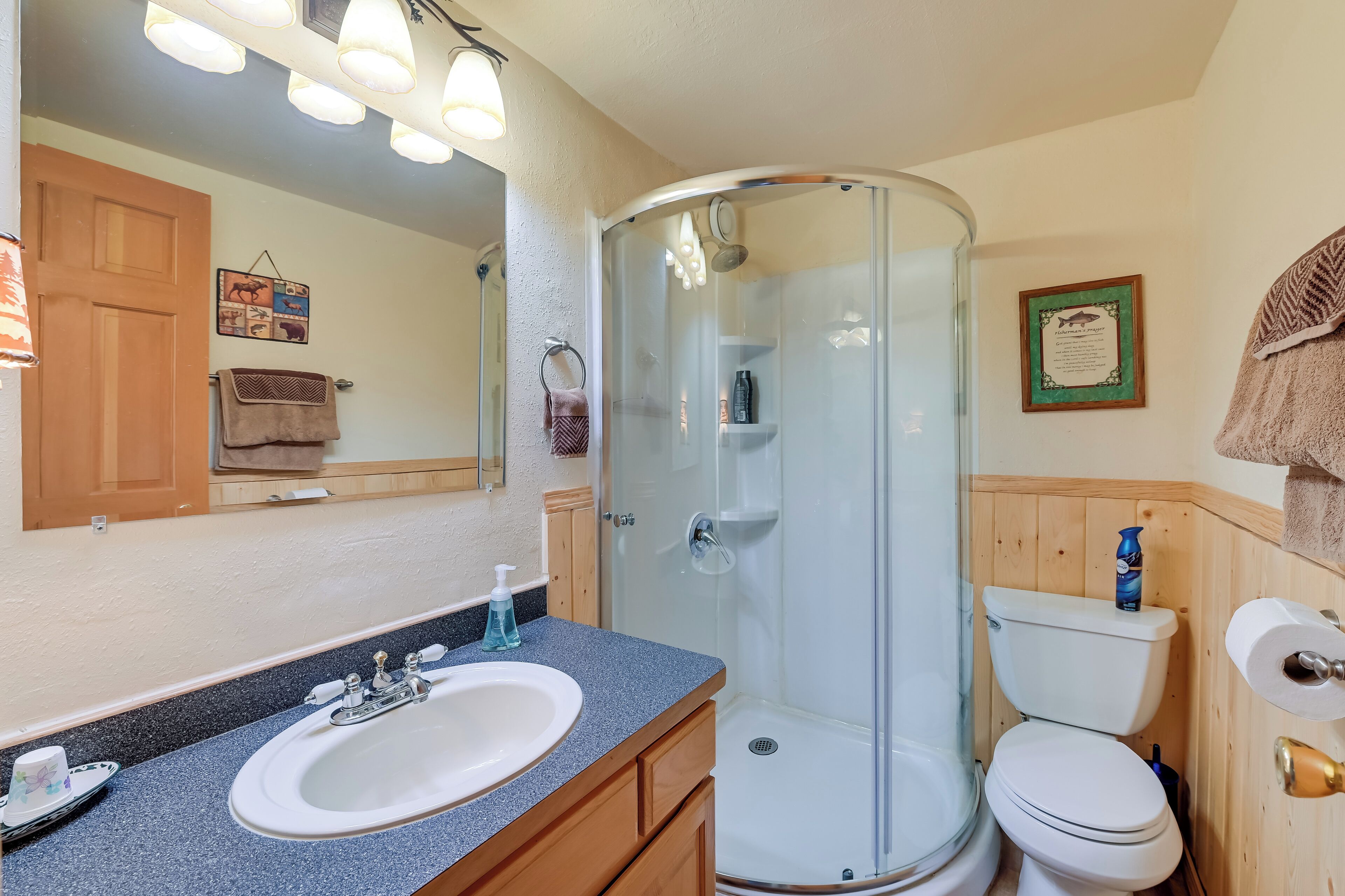 Ein Badezimmer mit Waschbecken, Spiegel, Dusche, Toilette und Holzausstattung.