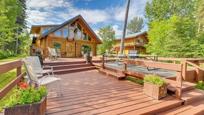 A wooden cabin with a deck, outdoor seating, and a scenic view of trees. - Soldotna Fishing Lodges w/ Dock on Kenai River! (Soldotna)
