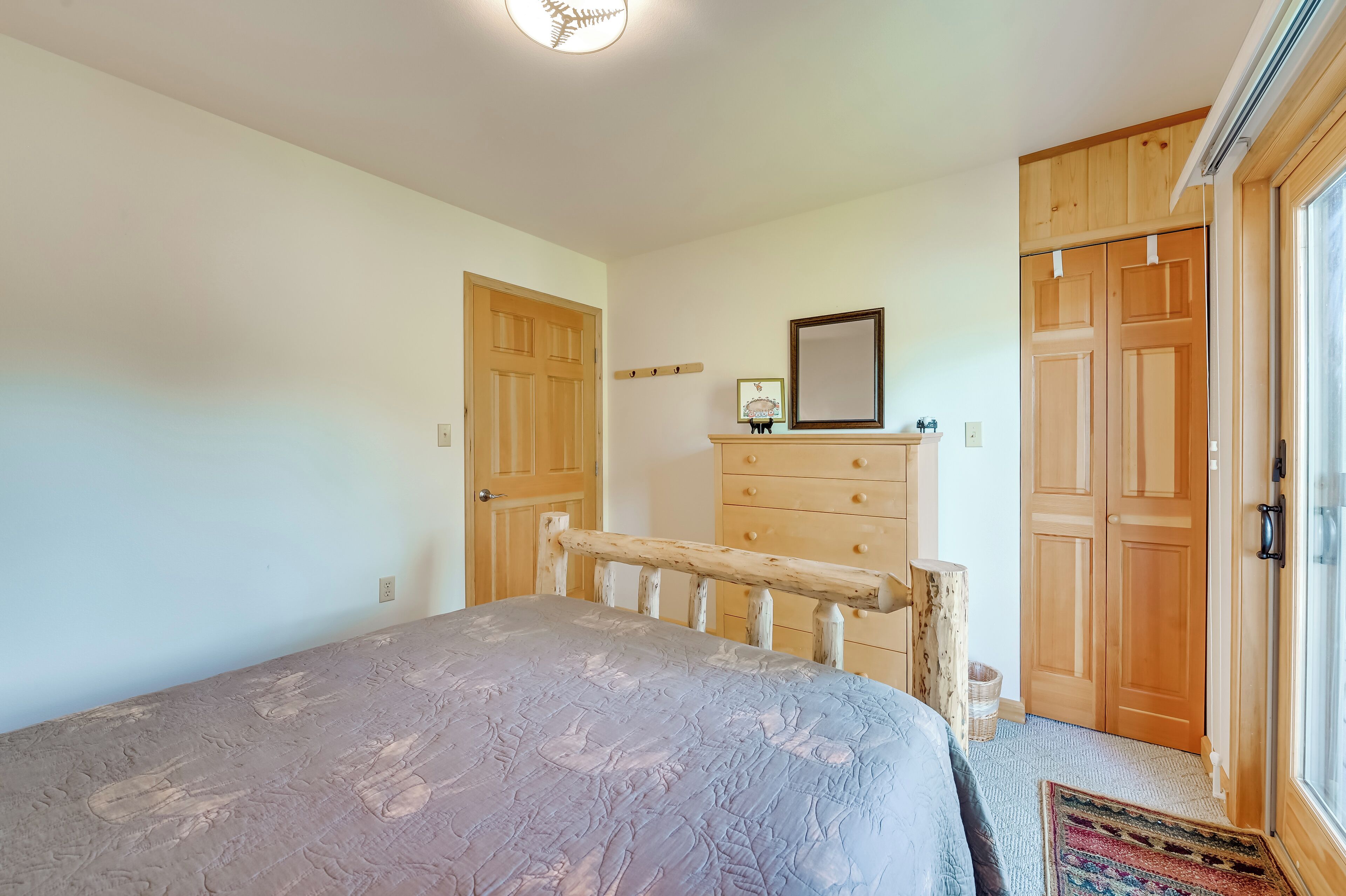 A bedroom with a bed, wooden wardrobe, and a dresser.