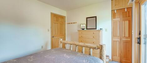 A bedroom with a bed, wooden wardrobe, and a dresser.
