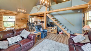 A log cabin interior with a living room, dining area, kitchen, and a staircase. - Soldotna Fishing Lodges w/ Dock on Kenai River! (Soldotna)