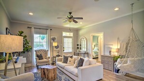 A spacious living room with a white sofa, a round wooden coffee table, and a hanging chair. - Baton Rouge Game Day House w/ Chic Yard Space (Baton Rouge)