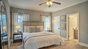 A bedroom with a large bed, a ceiling fan, and a nightstand with a lamp. - Baton Rouge Game Day House w/ Chic Yard Space (Baton Rouge)