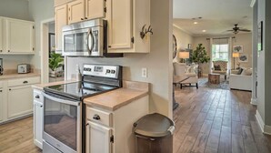 A modern kitchen with stainless steel appliances, white cabinetry, and a hardwood floor. - Baton Rouge Game Day House w/ Chic Yard Space (Baton Rouge)