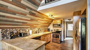 A kitchen with a wooden ceiling, a stone backsplash, and a central island. - Hillside Cripple Creek Cabin w/ Hot Tub, Mtn Views (Cripple Creek)