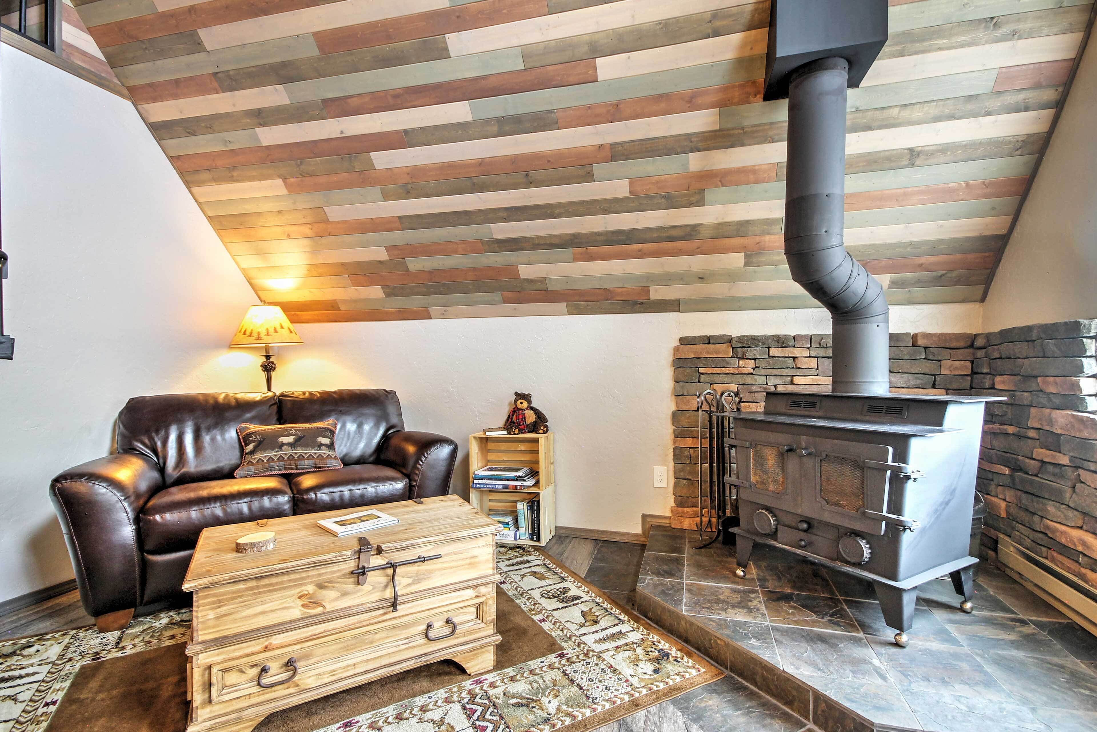 A cozy living room with a leather sofa, a wooden coffee table, and a fireplace with a stone wall.
