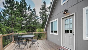 A deck with a table and chairs, a door, and a window. - Hillside Cripple Creek Cabin w/ Hot Tub, Mtn Views (Cripple Creek)