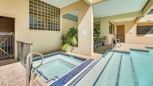 A pool area with multiple pools, a metal handrail, and a tiled floor.