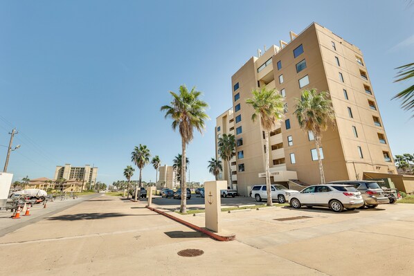 A multi-story building with a parking lot, palm trees, and a clear sky. - South Padre Island Vacation Rental Near Beach! (South Padre Island)