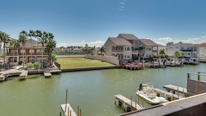 A marina with boats docked, a grassy area, and buildings with balconies.