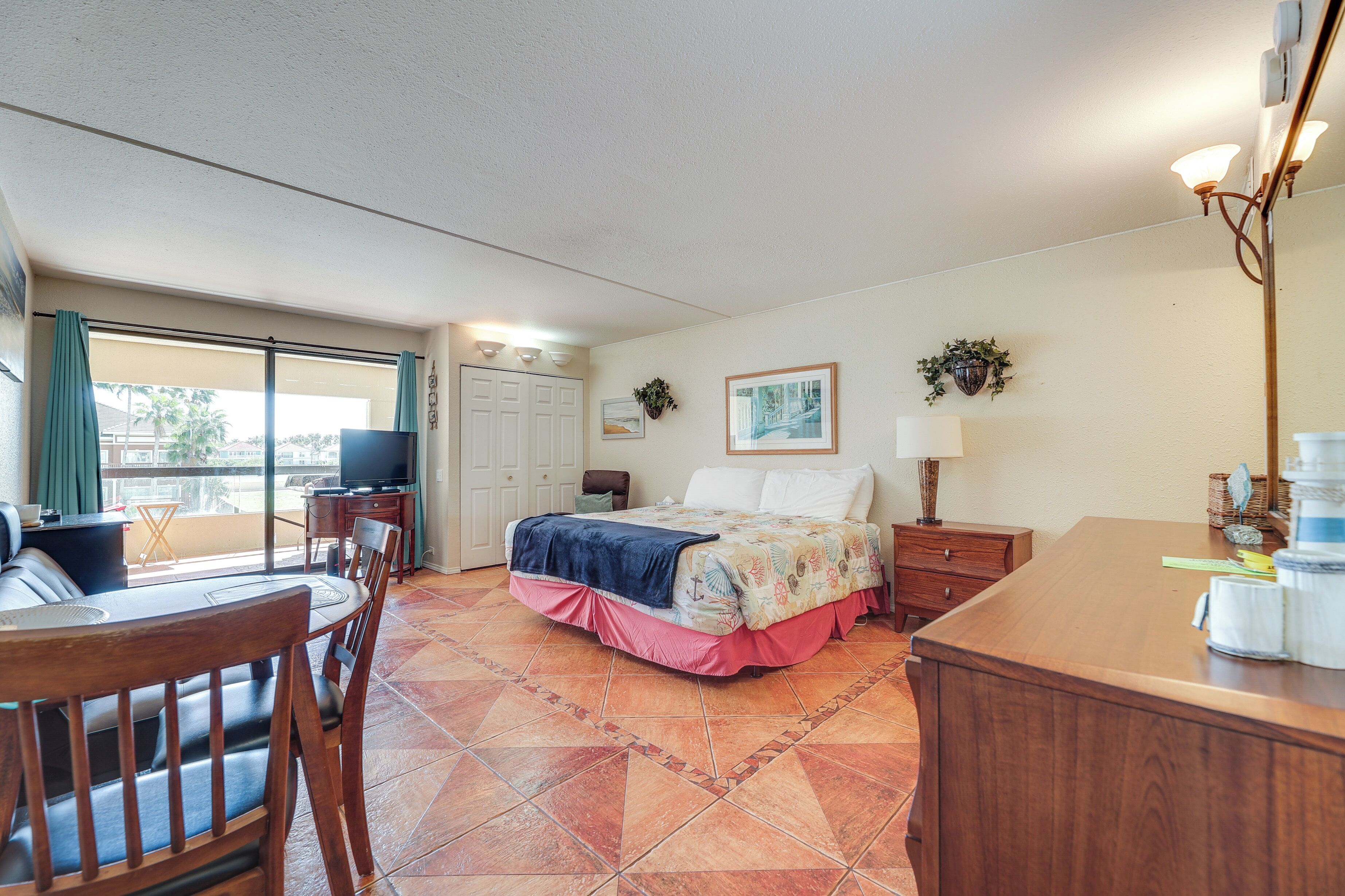 Une chambre d’hôtel avec un lit, un bureau, une chaise, une télévision et un balcon avec vue.