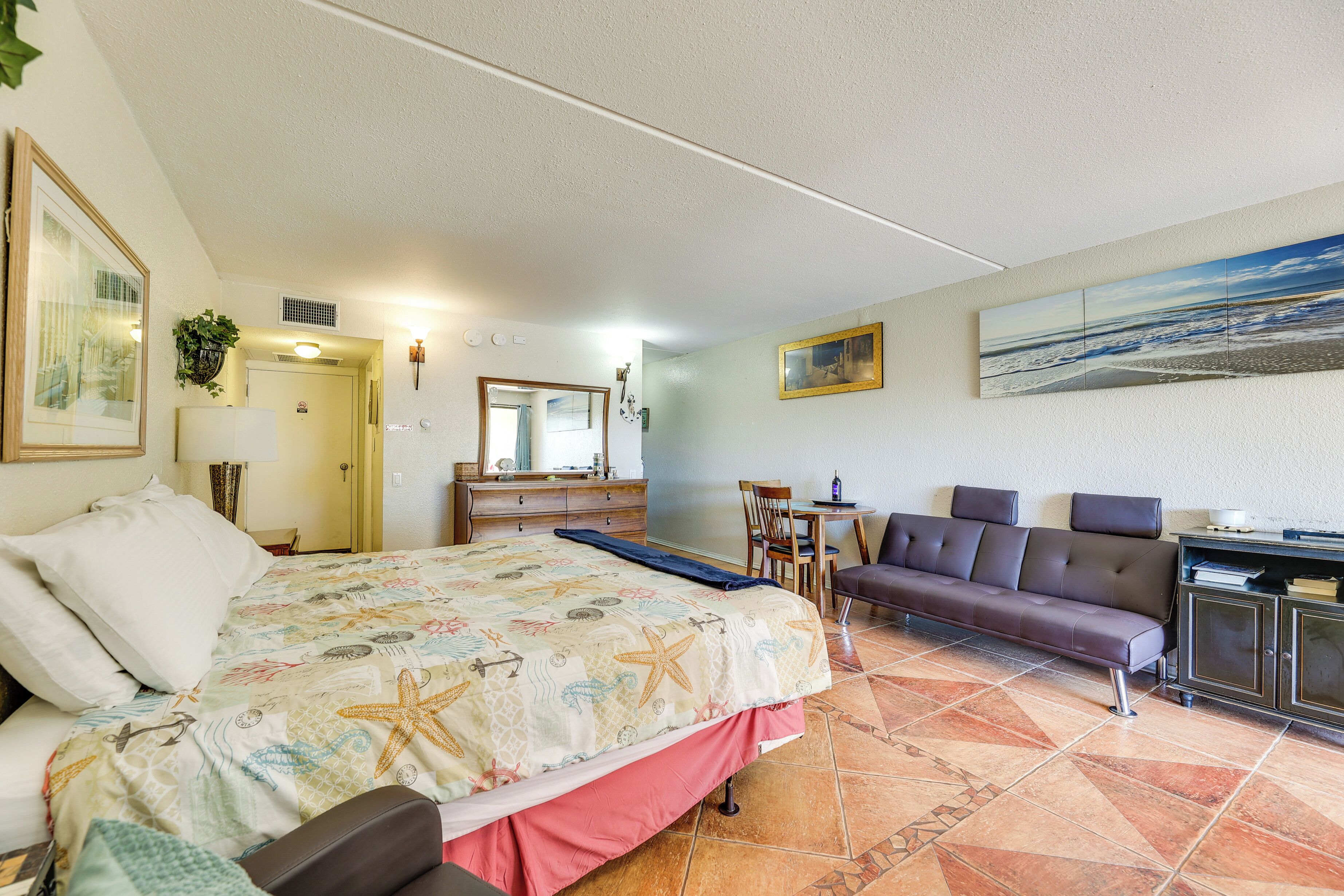 Una camera d'albergo con un letto, un divano, una scrivania e un quadro appeso al muro.