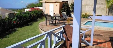 A wooden deck with outdoor furniture, a small building, and a pool.