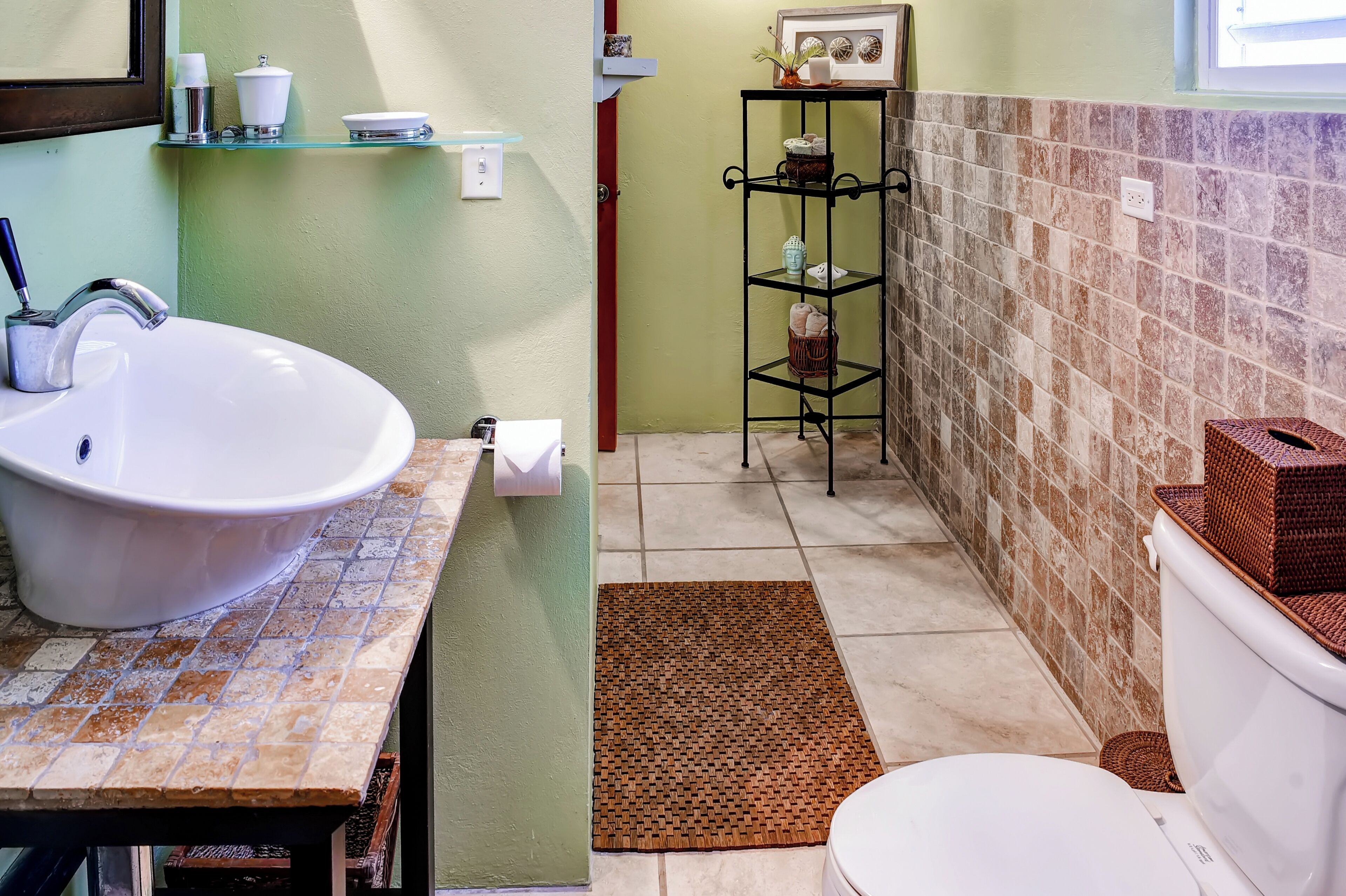 A bathroom with a white sink, toilet, and a shelf with toiletries.