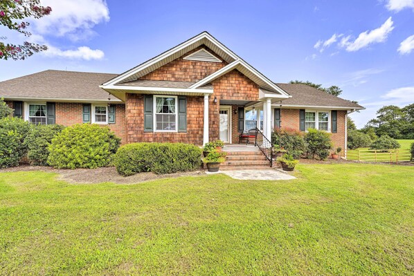 A two-story brick house with a front porch, a covered entryway, and a well-maintained lawn. - Family Getaway w/ Pier on Currituck Sound (Currituck)