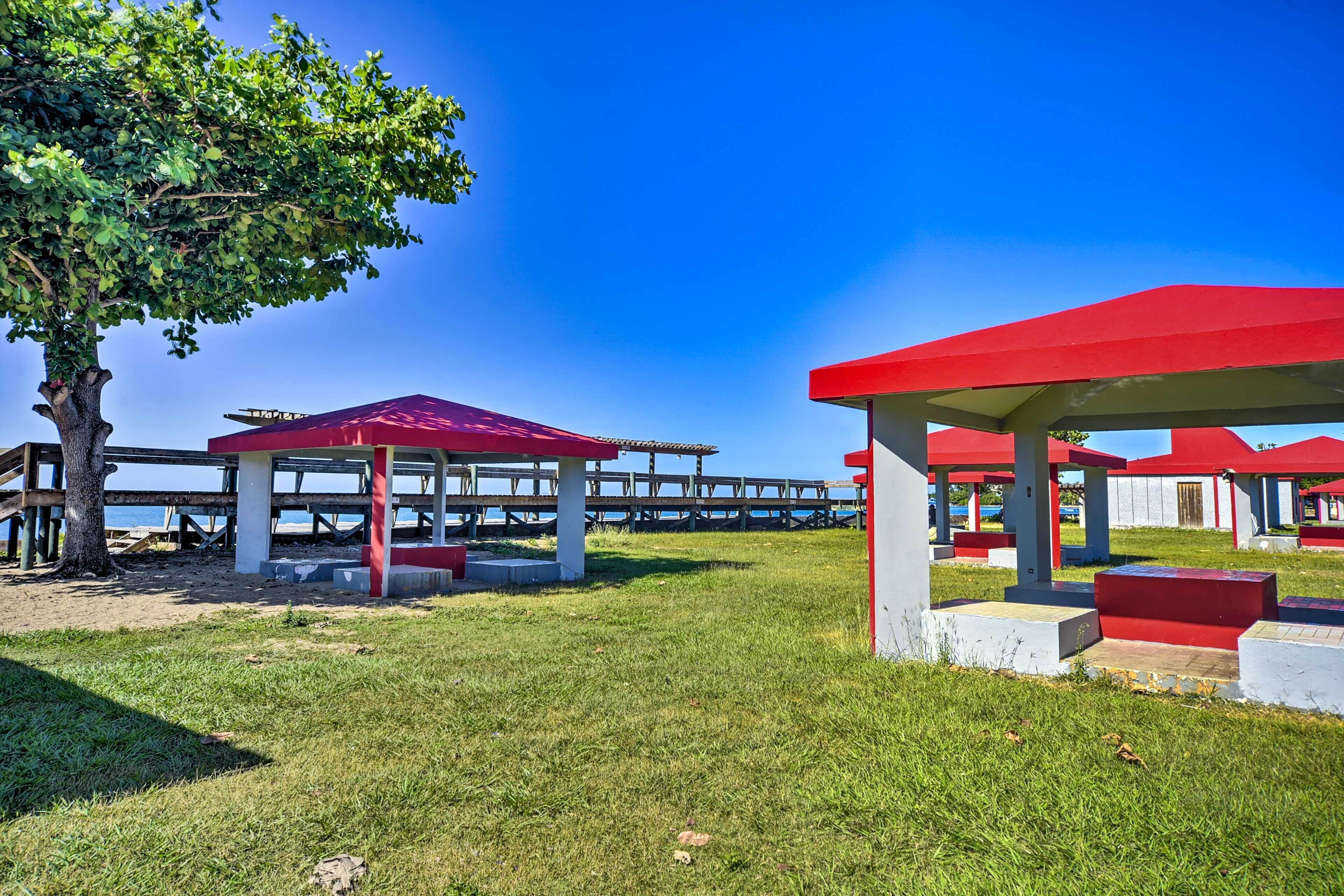 A beachside park with red structures and a wooden pier extending into the water.