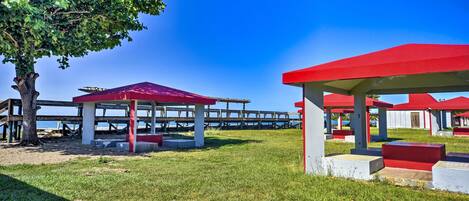 A beachside park with red structures and a wooden pier extending into the water.