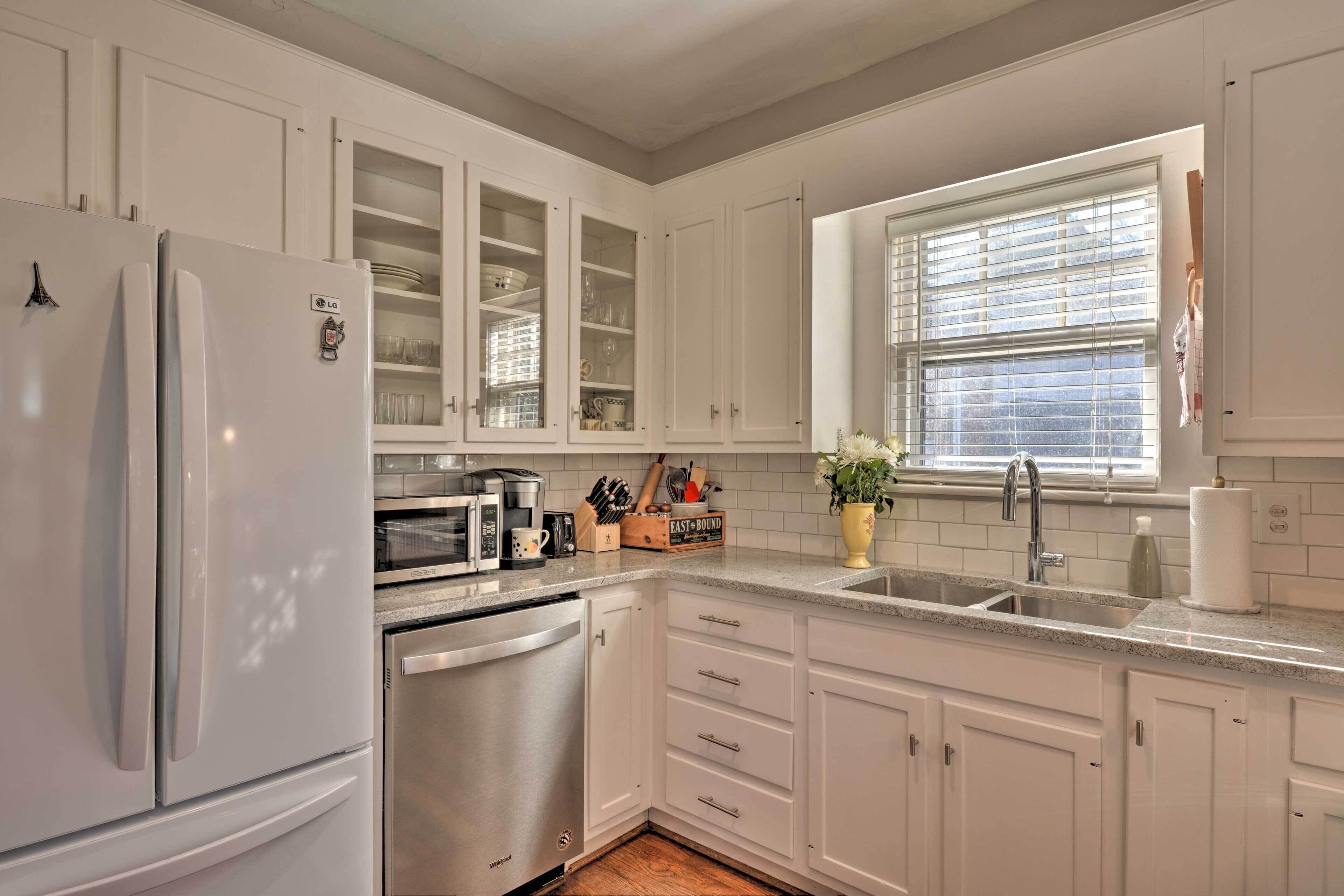 Una cocina moderna con armarios blancos, un refrigerador de acero inoxidable, un lavavajillas y un horno empotrado.