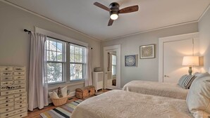 A bedroom with two beds, a ceiling fan, a dresser, a window with curtains, and a mirror. - Vintage Chic Cottage < 1 Mile to UNC Greensboro! (Greensboro)