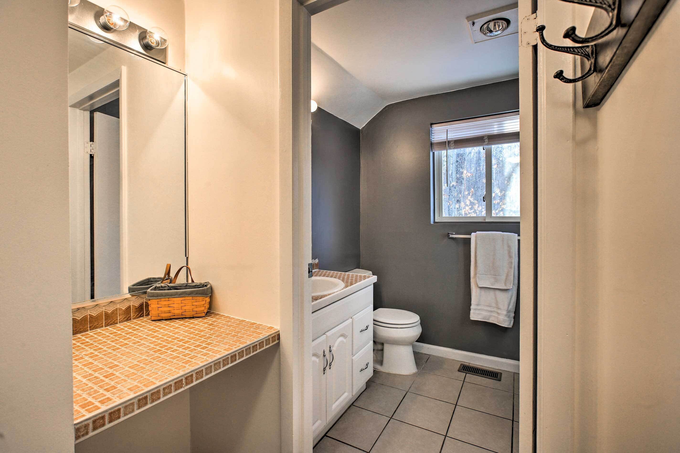 A bathroom with a white sink, a mirror, a window, and a towel rack.