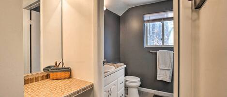 A bathroom with a white sink, a mirror, a window, and a towel rack.