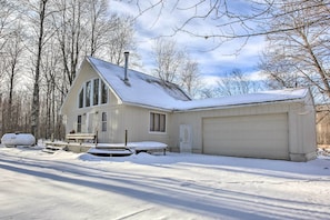 A two-story house with a garage, surrounded by snow-covered ground and trees.