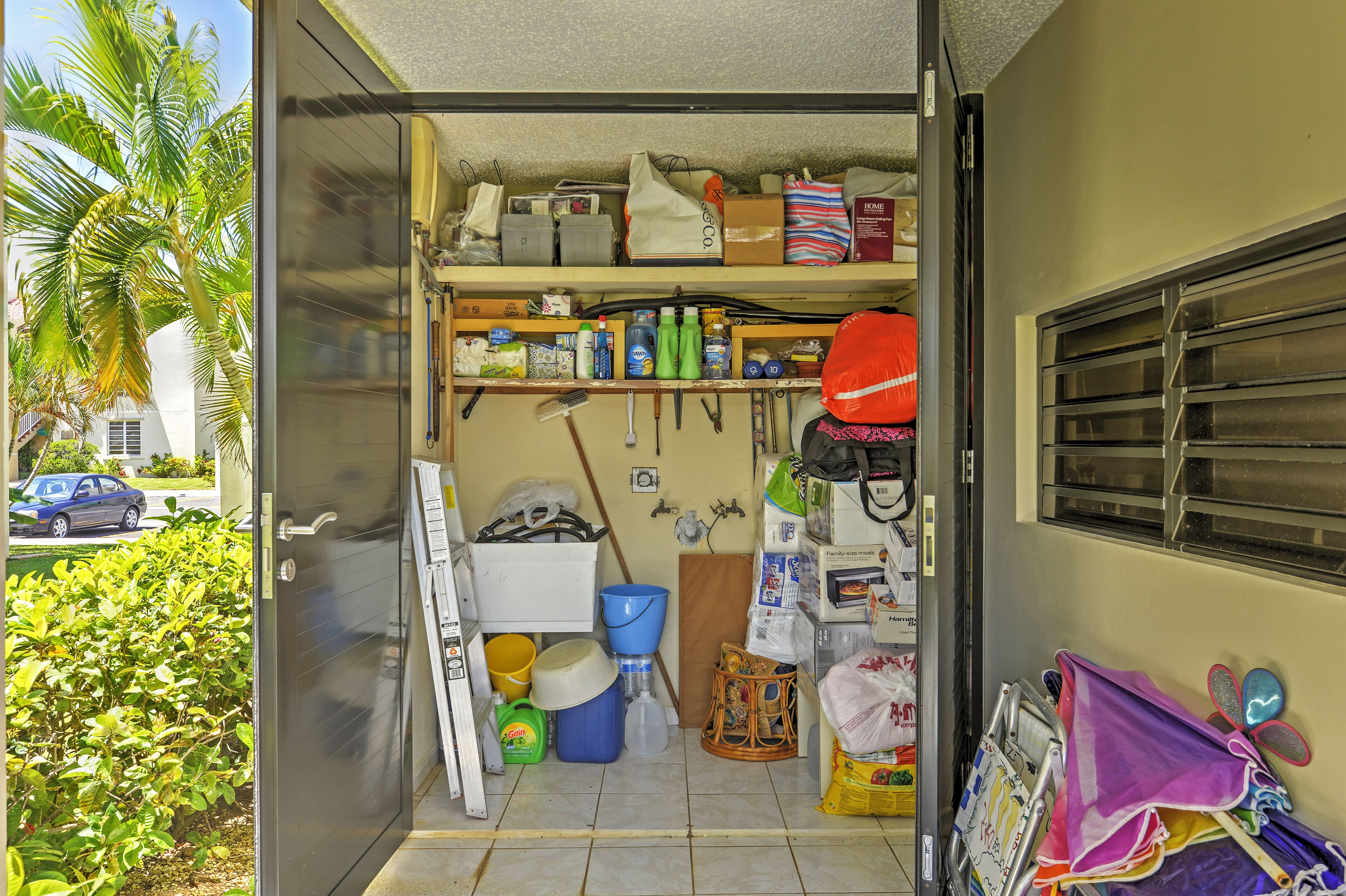 A compact storage area with shelves, bins, and various household items.