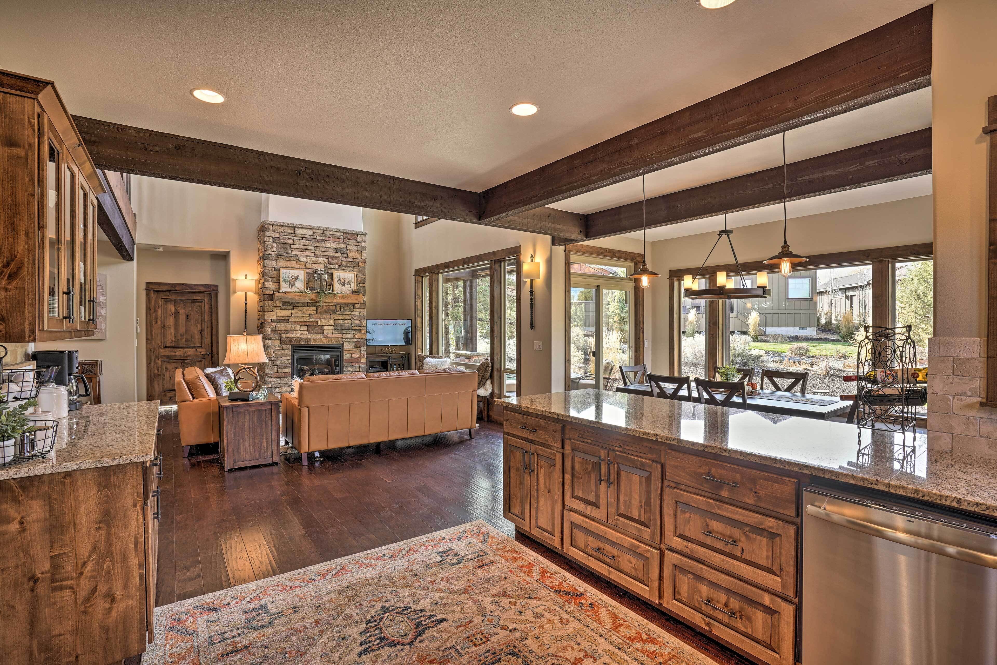 A spacious kitchen with a large island, wooden cabinets, and a stone fireplace.