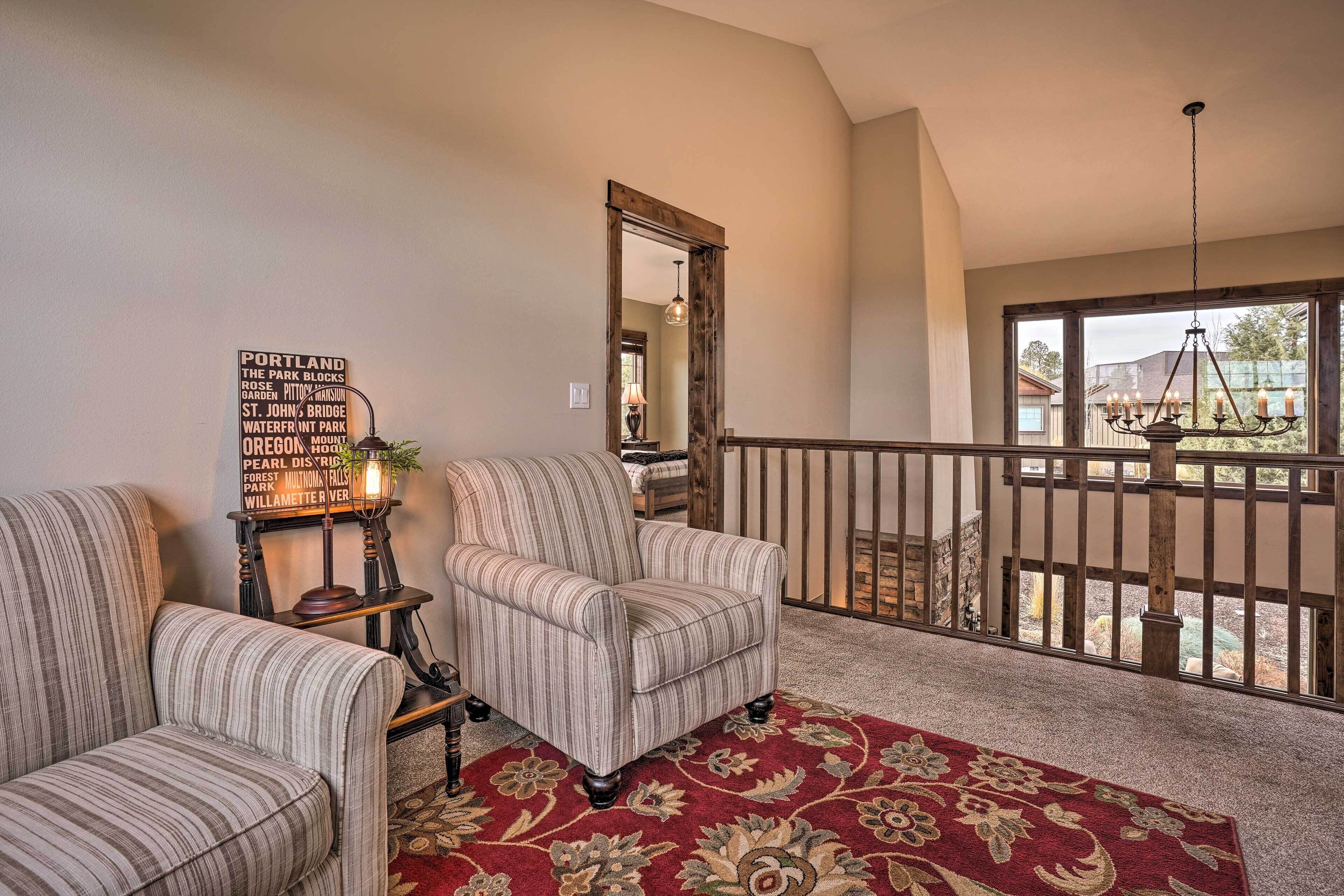 A living room with a red floral carpet, two striped armchairs, a vintage lamp, and a sign listing Portland attractions.