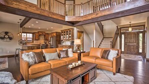 A spacious living area with a large sectional sofa, a wooden coffee table, and a high ceiling with exposed beams. - Modern Eagle Crest Escape w/ Patio & 2 Balconies! (Redmond)